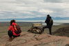 Pai e filha no Mirador de las Águilas, na Patagônia, com mochilas Allca Allcatrazes: ela agachada fotografando e ele em pé diante do lago e da cordilheira