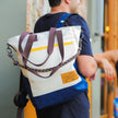 Tote Bag Allcatrazes Allca x Brasco Off White Encontro em tecido hidrorrepelente usada como mochila nas costas - foto lifestyle do modo aventura urbana