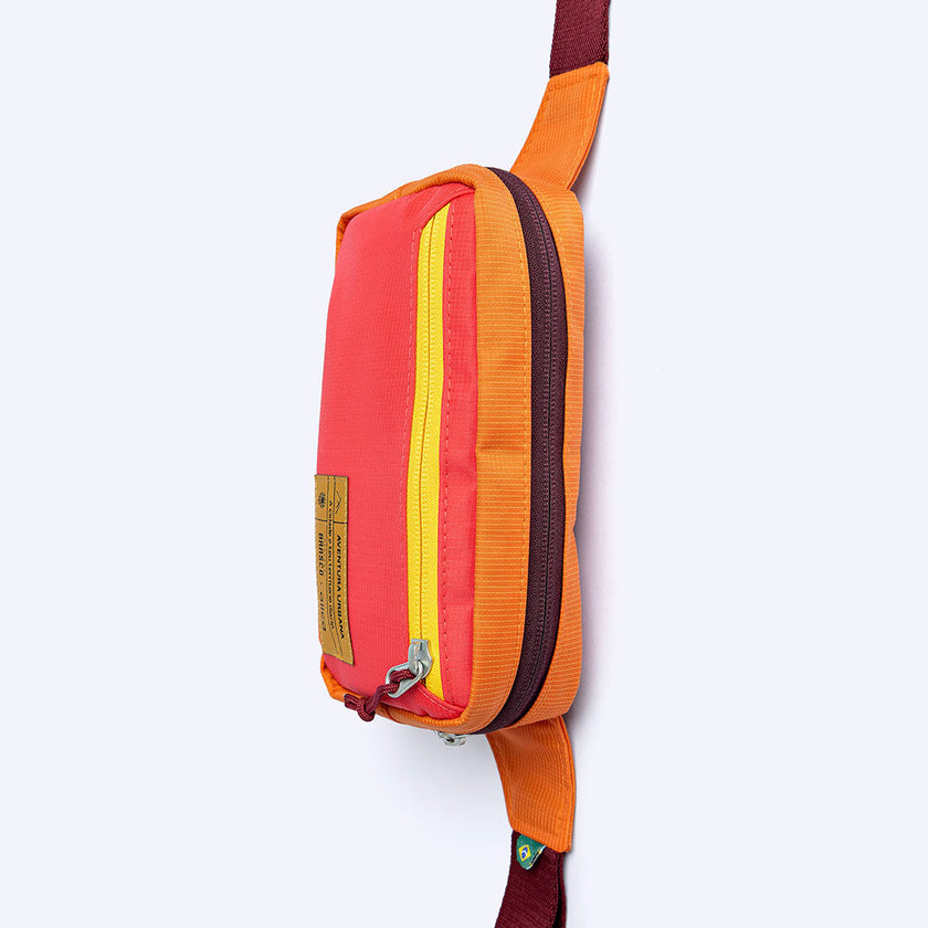 Pochete Allcatrazes Allca x Brasco Coral Esquina coral e laranja com alça regulável bordô e fivela, vista lateral feita no Brasil