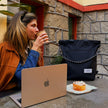 mulher tomando café em uma loja de Croissants artesanais chamada sfoglia com macbook trabalhando anywhere office com a tote eclipse e um cinamon roll
